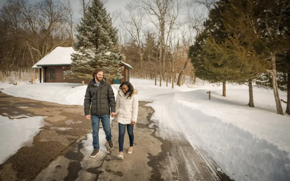 A couple walk along a path surrounded by snow