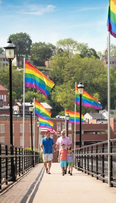 People walking down the bridge with flags along it