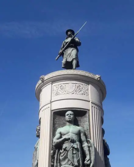 A weathered bronze statue of a World War I-era "doughboy" solider adop a granite plinth