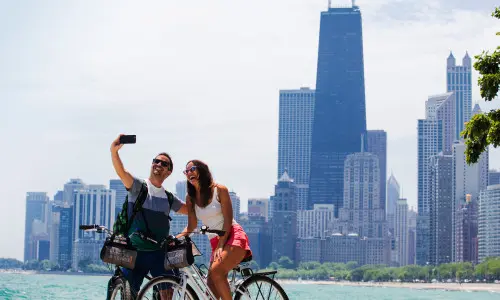 A couple riding bikes and taking a photo along the Chicago lakefront