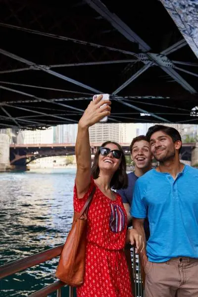 People posing for a photo by river under bridge
