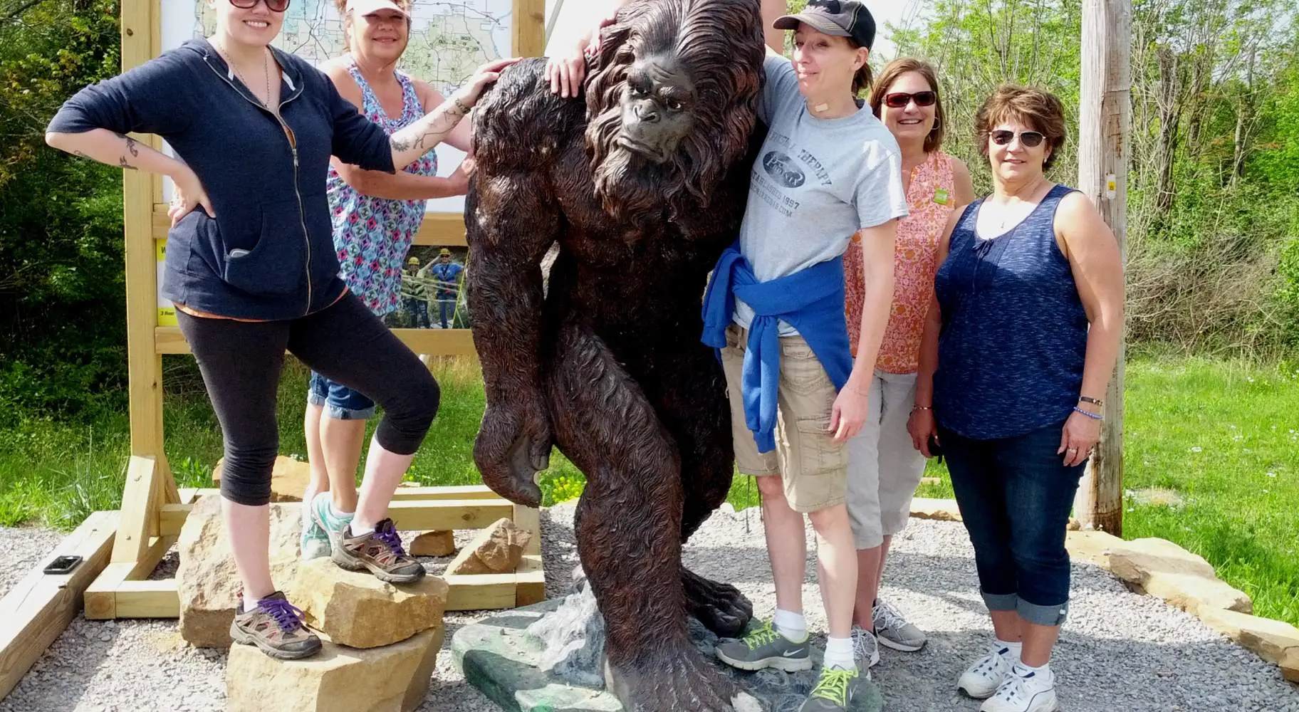 A group of six women posing with a statue of a sasquatch named Sassy